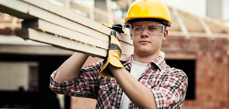 Carpenter carrying wood at a construction site.